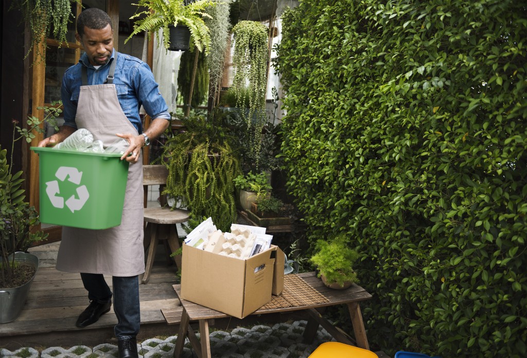 man carrying recycling bin