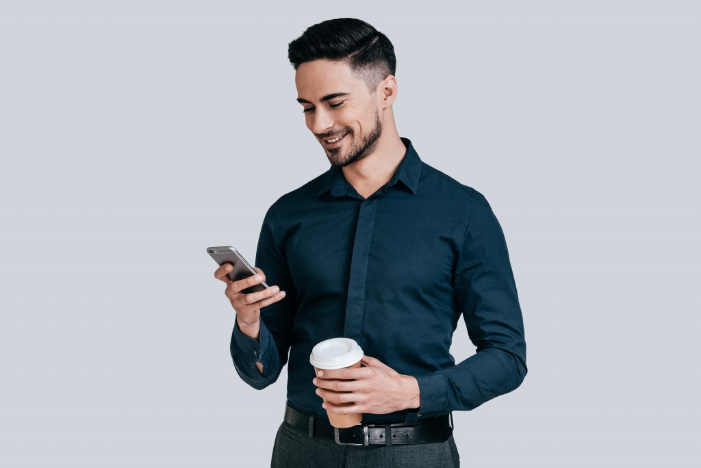 man smiling while using his phone