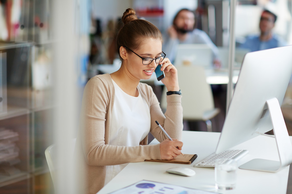 woman on telephone while writing a note