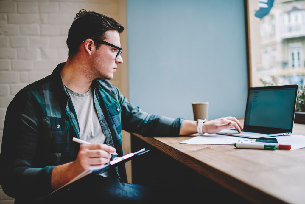 entrepreneur using a laptop while taking notes in an office