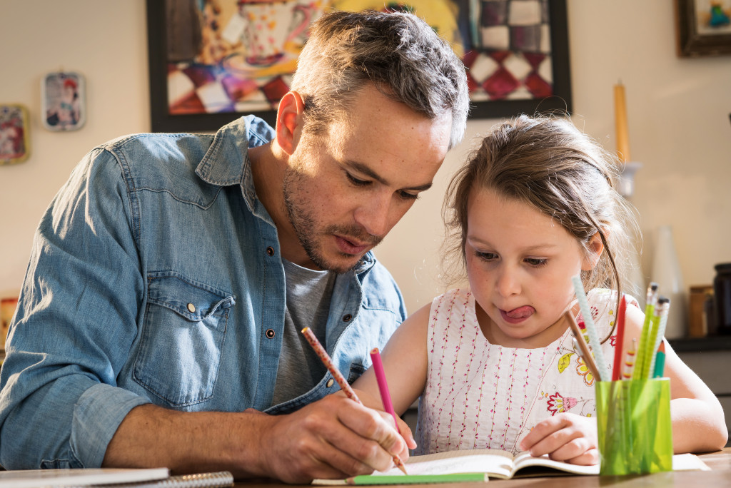 a father helping his young daughter do her homework