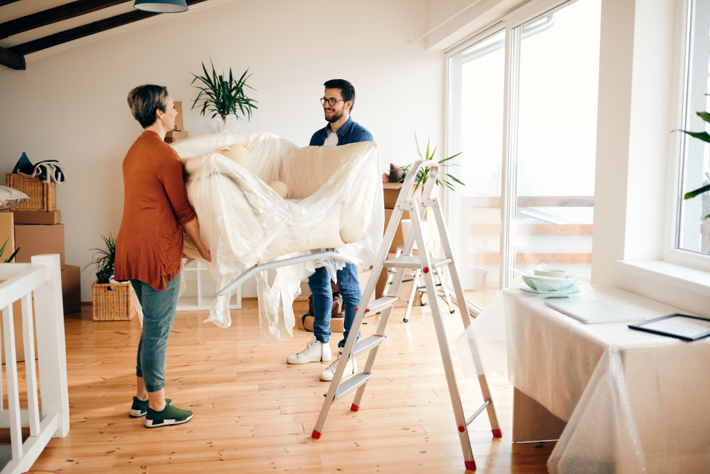 a couple carrying a sofa