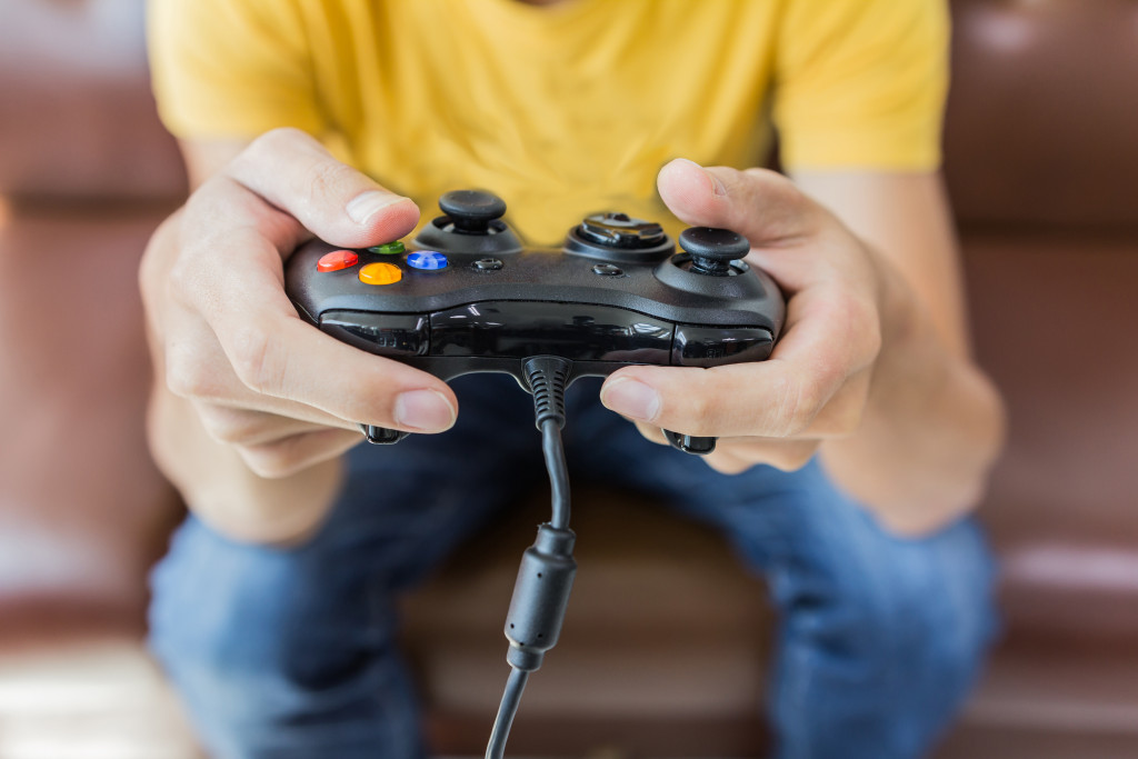 A teen holding a video game controller on the couch at home