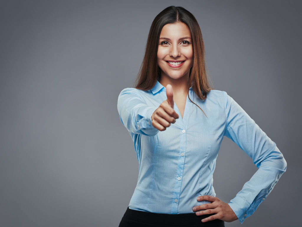 Neatly dressed woman giving camera a thumbs up