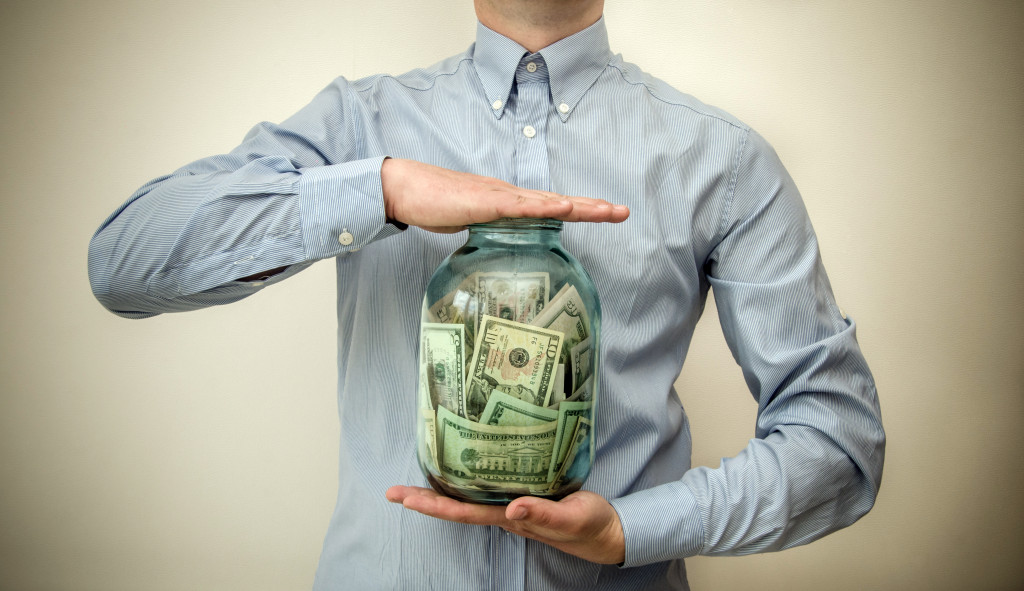 A businessman holding a jar full of money