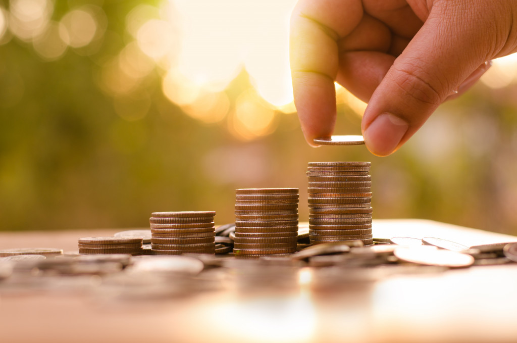 person adding gold coins into the highest stack at the right 