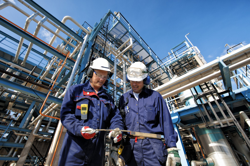 Two workers checking a tool outside a factory