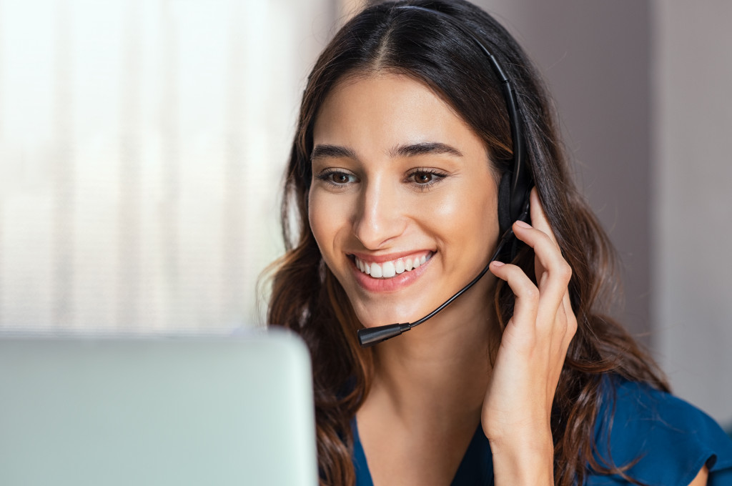 A woman talking to a customer using a laptop