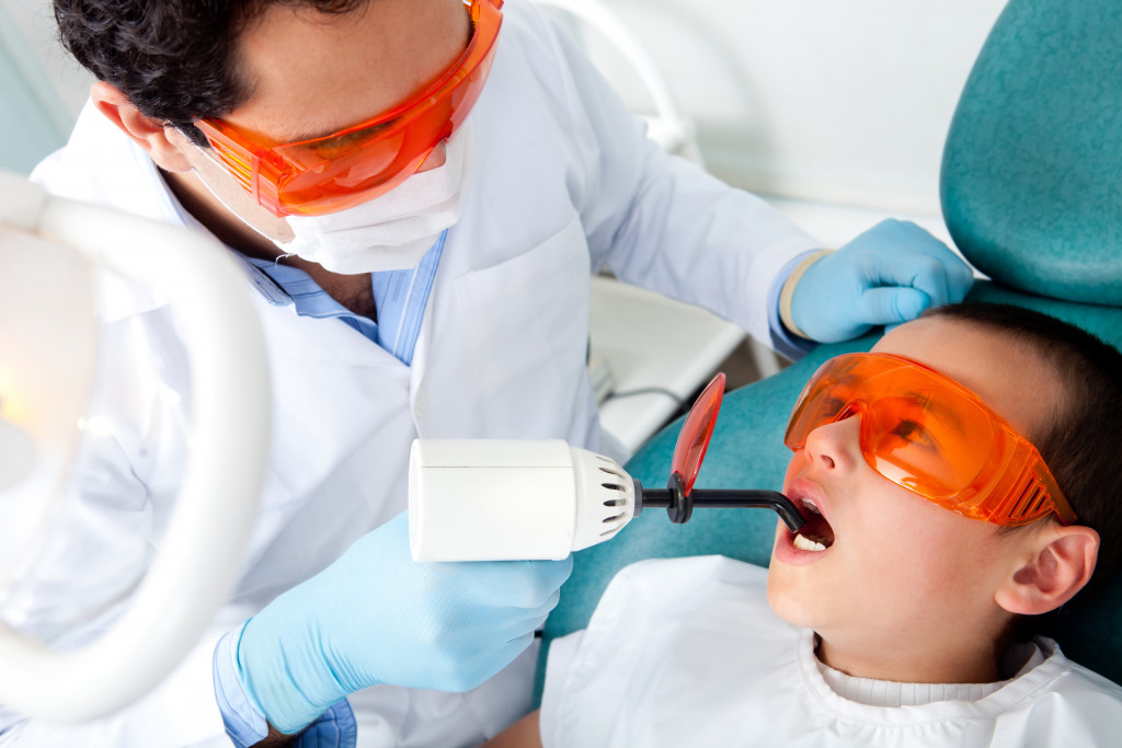 dentist and young patient wearing goggles for safety when using laser light