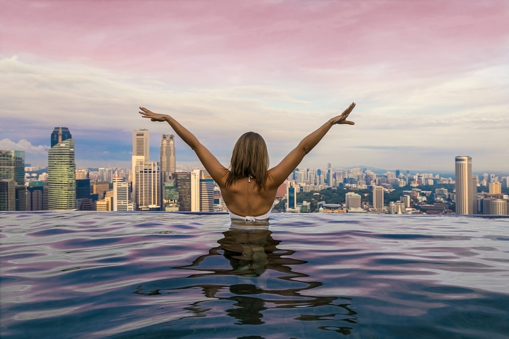 A young woman posing in an infinity pool with a city view